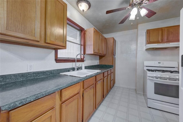5802 Riley Dr, Corpus Christi, TX 78412 - kitchen with white range with gas cooktop, dark countertops, light floors, ceiling fan, and under cabinet range hood