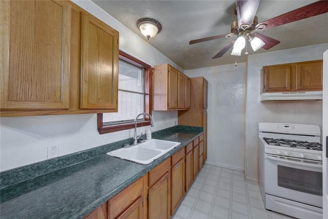 5802 Riley Dr, Corpus Christi, TX 78412 - kitchen featuring white gas stove, under cabinet range hood, light floors, dark countertops, and a ceiling fan