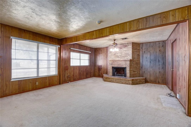 5802 Riley Dr, Corpus Christi, TX 78412 - unfurnished living room with wood walls, a ceiling fan, a textured ceiling, carpet, and a fireplace