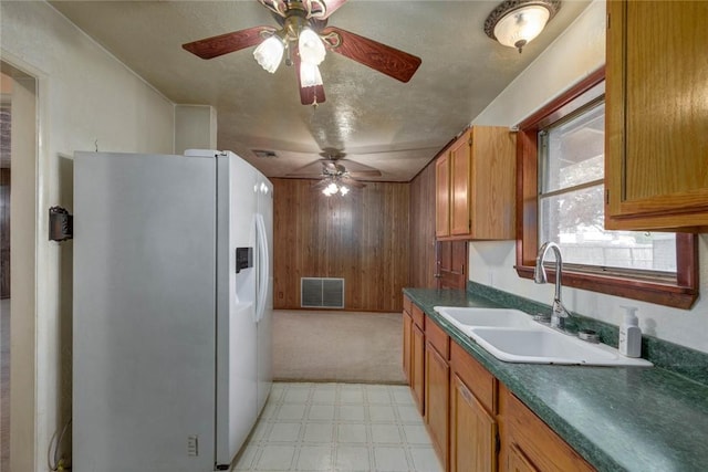 5802 Riley Dr, Corpus Christi, TX 78412 - kitchen with white fridge with ice dispenser, ceiling fan, dark countertops, light floors, and brown cabinetry