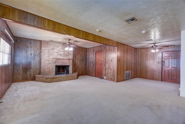 5802 Riley Dr, Corpus Christi, TX 78412 - unfurnished living room featuring a ceiling fan, wood walls, a textured ceiling, carpet, and a brick fireplace