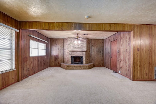 5802 Riley Dr, Corpus Christi, TX 78412 - unfurnished living room featuring a textured ceiling, carpet, wood walls, a ceiling fan, and a fireplace