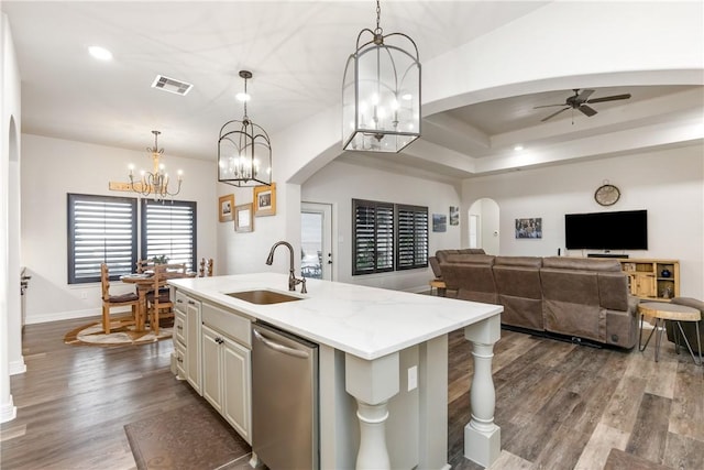 kitchen with a center island with sink, sink, stainless steel dishwasher, decorative light fixtures, and light stone counters