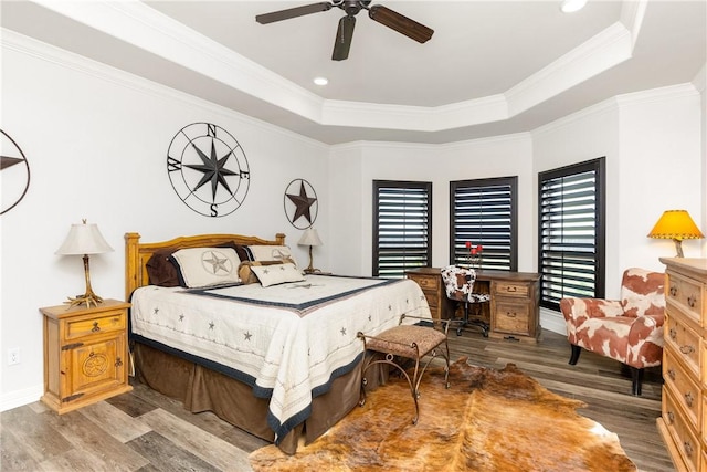 bedroom with a tray ceiling, hardwood / wood-style flooring, ornamental molding, and ceiling fan