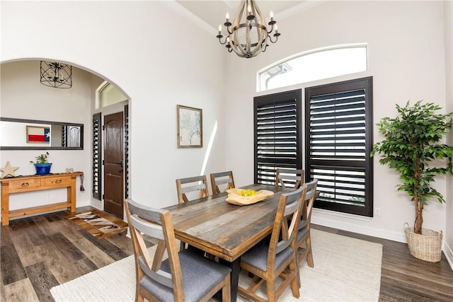 dining area with an inviting chandelier, dark wood-type flooring, and ornamental molding