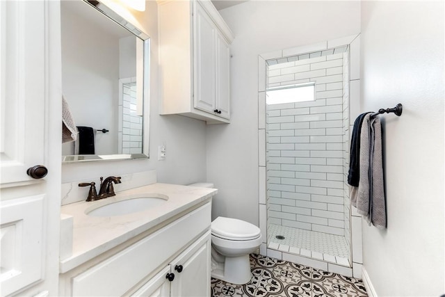 bathroom with tiled shower, vanity, toilet, and tile patterned flooring