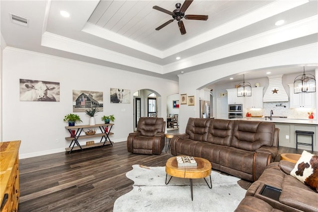 living room with crown molding, dark hardwood / wood-style flooring, sink, and a tray ceiling