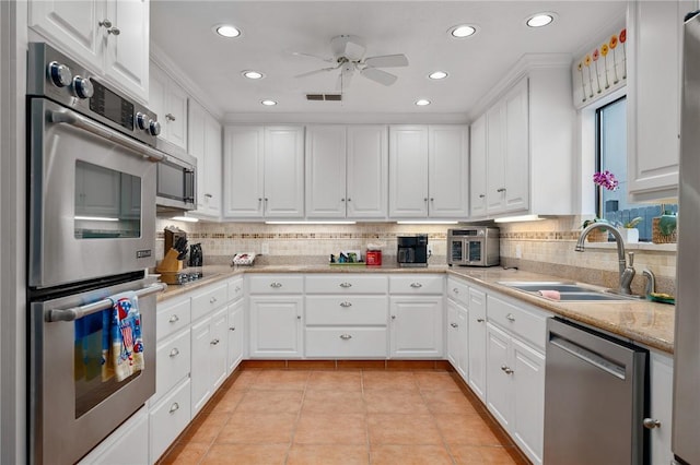 kitchen featuring tasteful backsplash, white cabinets, appliances with stainless steel finishes, and sink