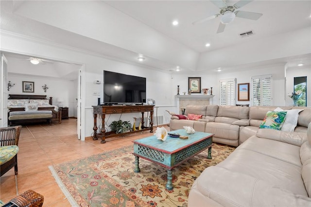 tiled living room with ceiling fan and a tray ceiling