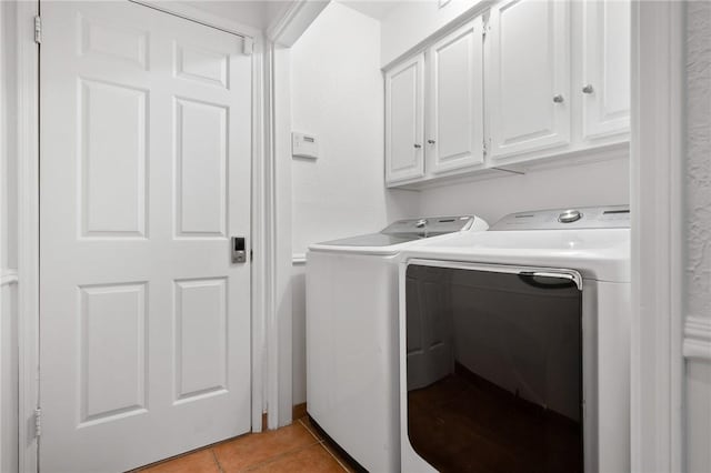 laundry room with light tile patterned floors, washing machine and dryer, and cabinets