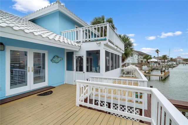 deck featuring french doors, a sunroom, and a water view