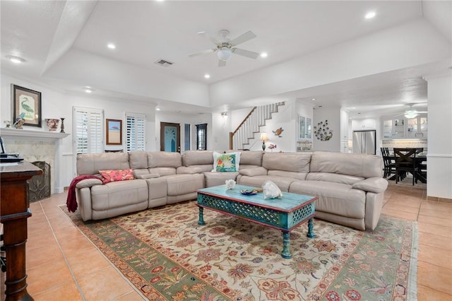 tiled living room with ceiling fan and a tray ceiling