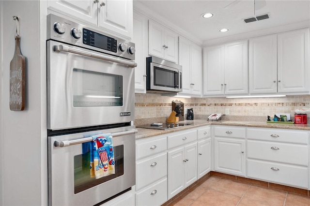 kitchen featuring white cabinets, backsplash, light tile patterned floors, and stainless steel appliances