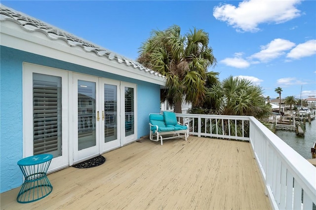 wooden deck with a water view and french doors