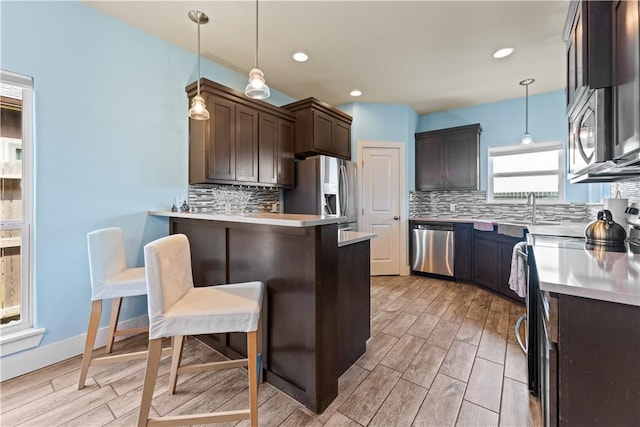 7338 Allman Dr, Corpus Christi, TX 78414 - kitchen featuring appliances with stainless steel finishes, dark brown cabinetry, tasteful backsplash, a peninsula, and a breakfast bar