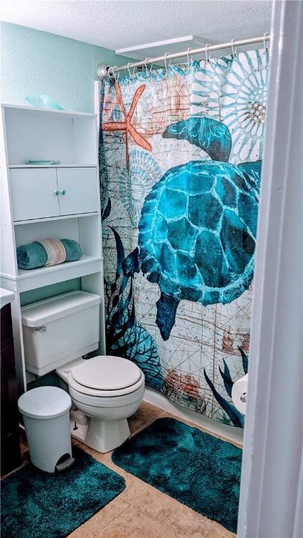 3938 Surfside Blvd Unit 2236, Corpus Christi, TX 78402 - bathroom with a textured ceiling, toilet, tile patterned floors, and curtained shower