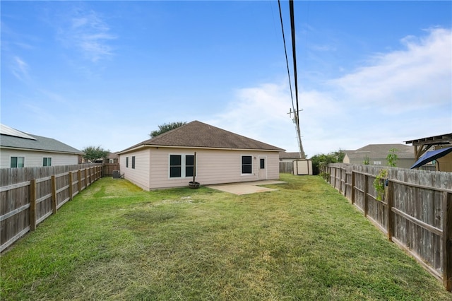 rear view of house featuring a patio, a lawn, and a storage unit