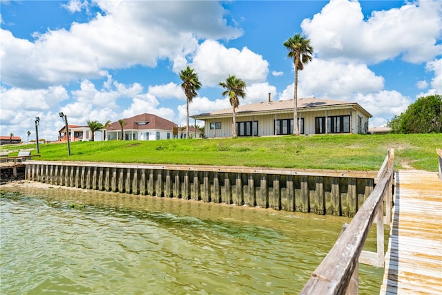 view of dock with a yard and a water view