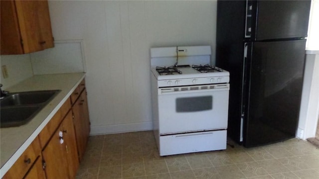 810 S 10th St, Kingsville, TX 78363 - kitchen featuring white gas range, freestanding refrigerator, brown cabinets, and light countertops