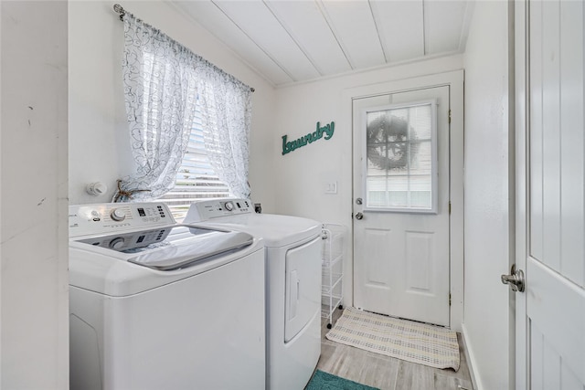 laundry area with a healthy amount of sunlight, separate washer and dryer, and hardwood / wood-style floors