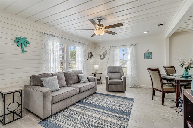 living room featuring wood ceiling, a wealth of natural light, ceiling fan, and wood walls