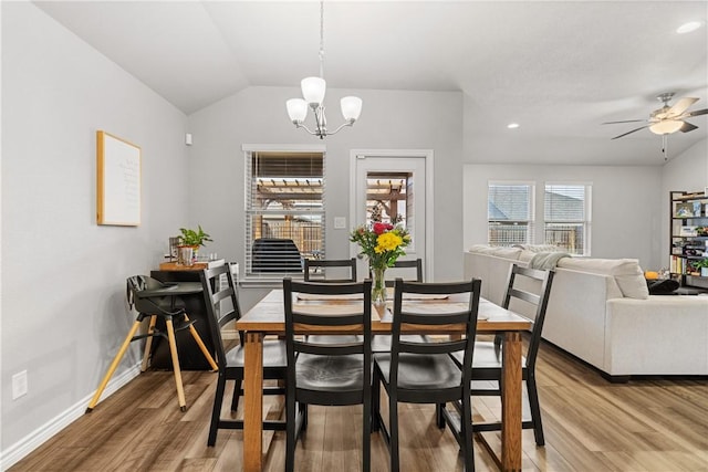 dining room with ceiling fan with notable chandelier, vaulted ceiling, and hardwood / wood-style floors