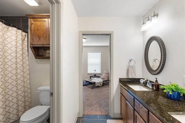 bathroom featuring double vanity, curtained shower, a sink, and toilet