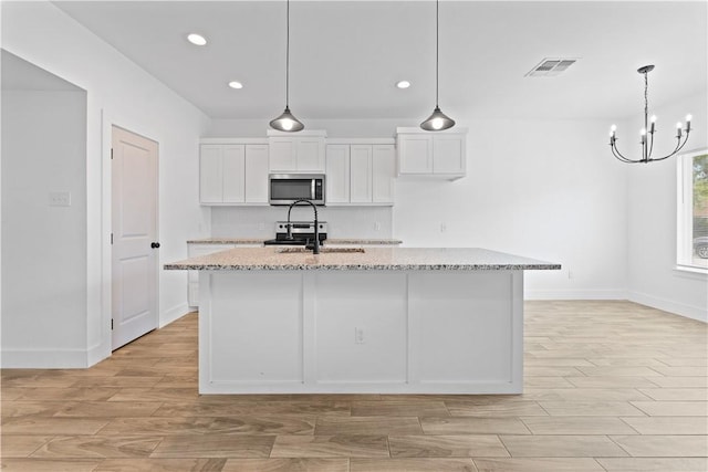 4209 Walnut Hills Dr, Corpus Christi, TX 78413 - kitchen with stainless steel appliances, a sink, light stone counters, white cabinetry, and light wood finished floors
