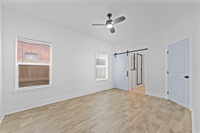 4209 Walnut Hills Dr, Corpus Christi, TX 78413 - spare room featuring a barn door, light wood-style floors, a ceiling fan, and baseboards