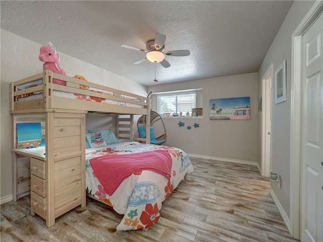 bedroom featuring ceiling fan, wood-type flooring, and a textured ceiling