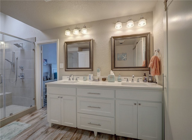 bathroom with vanity, hardwood / wood-style floors, a textured ceiling, and walk in shower