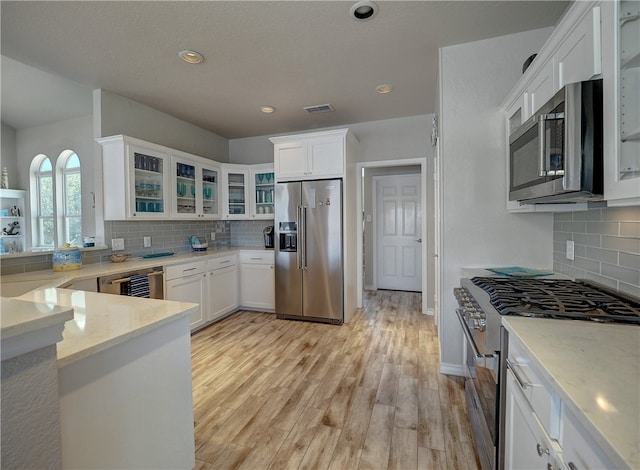 kitchen featuring white cabinetry, backsplash, light stone countertops, and high quality appliances