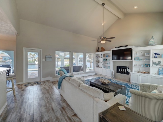 living room with beamed ceiling, ceiling fan, and high vaulted ceiling