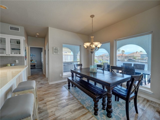 dining area with light hardwood / wood-style floors and a notable chandelier