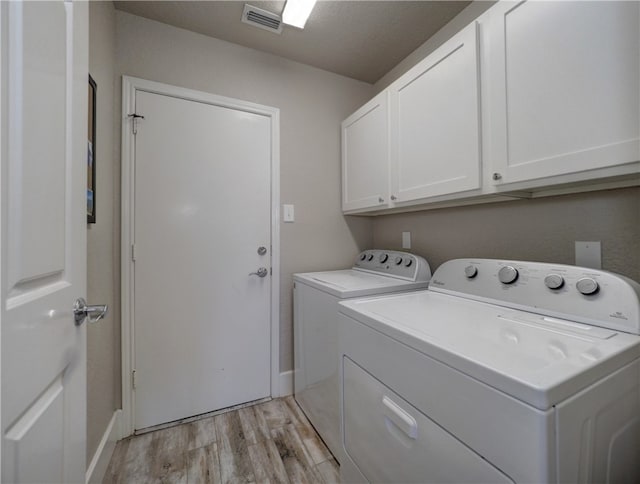 laundry room featuring cabinets, washer and clothes dryer, and light hardwood / wood-style floors