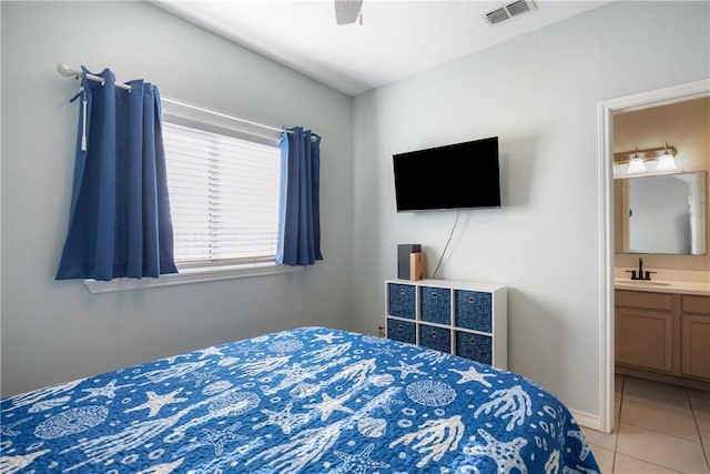 bedroom featuring light tile patterned floors, visible vents, ensuite bathroom, ceiling fan, and a sink