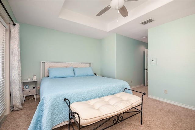 bedroom featuring a raised ceiling, visible vents, light carpet, and baseboards