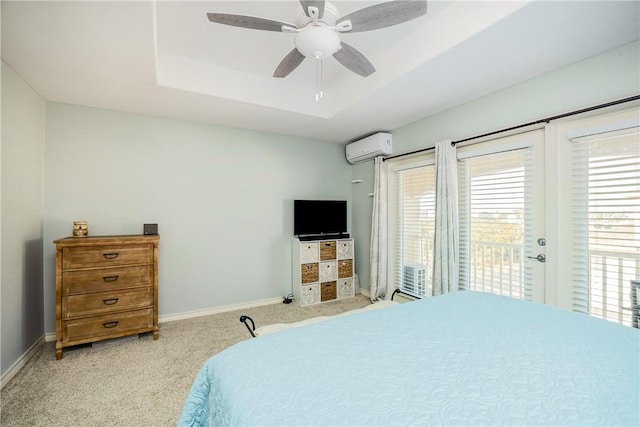 bedroom featuring access to exterior, baseboards, a tray ceiling, and an AC wall unit