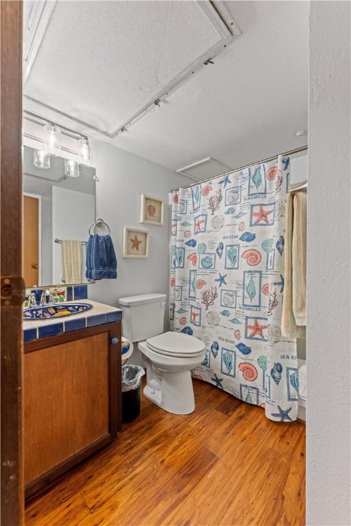 3938 Surfside Blvd Unit 3118, Corpus Christi, TX 78402 - bathroom with a textured ceiling, vanity, wood finished floors, and a shower with shower curtain