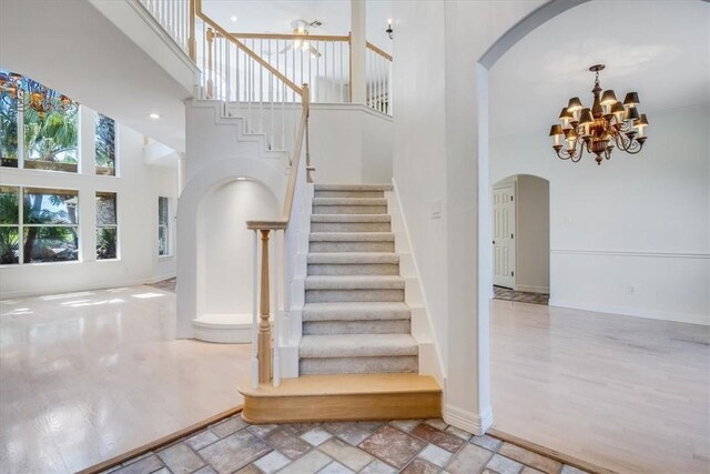 6302 Grandvilliers Dr, Corpus Christi, TX 78414 - staircase featuring a towering ceiling, arched walkways, a chandelier, and wood finished floors