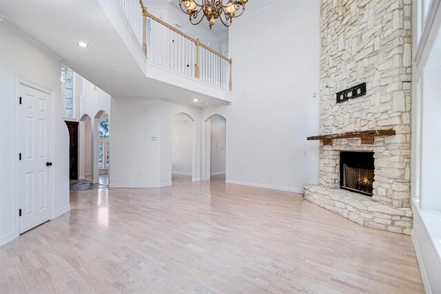 6302 Grandvilliers Dr, Corpus Christi, TX 78414 - unfurnished living room with arched walkways, a high ceiling, a stone fireplace, a chandelier, and wood finished floors