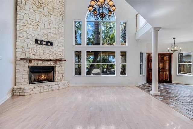 6302 Grandvilliers Dr, Corpus Christi, TX 78414 - unfurnished living room with a chandelier, decorative columns, a towering ceiling, a fireplace, and wood finished floors