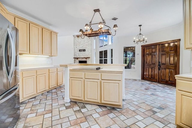 6302 Grandvilliers Dr, Corpus Christi, TX 78414 - kitchen with a chandelier, stainless steel fridge, light brown cabinets, a stone fireplace, and light countertops