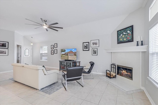 living area featuring baseboards, a tiled fireplace, lofted ceiling, ceiling fan, and light tile patterned flooring