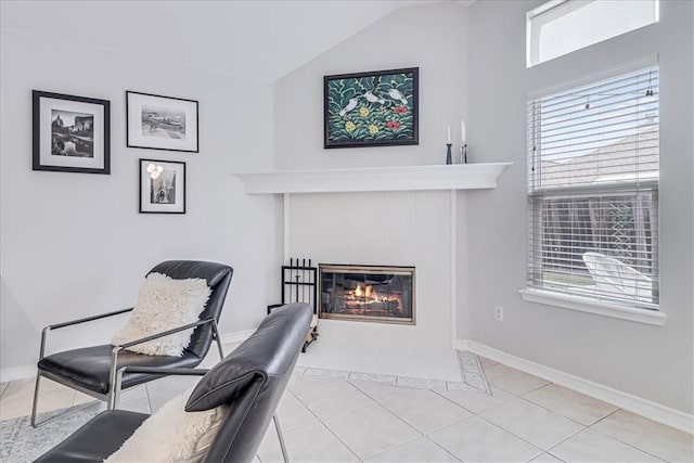 living area with lofted ceiling, light tile patterned floors, baseboards, and a tile fireplace