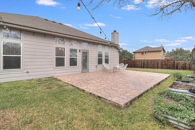 rear view of property featuring a yard, a patio area, fence, and a chimney