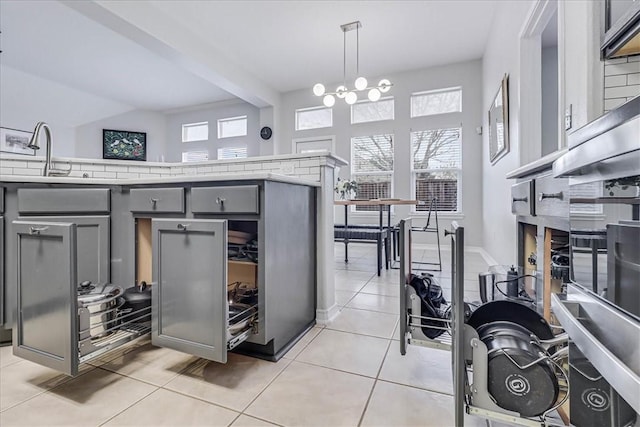 kitchen with a healthy amount of sunlight, pendant lighting, light countertops, and gray cabinetry