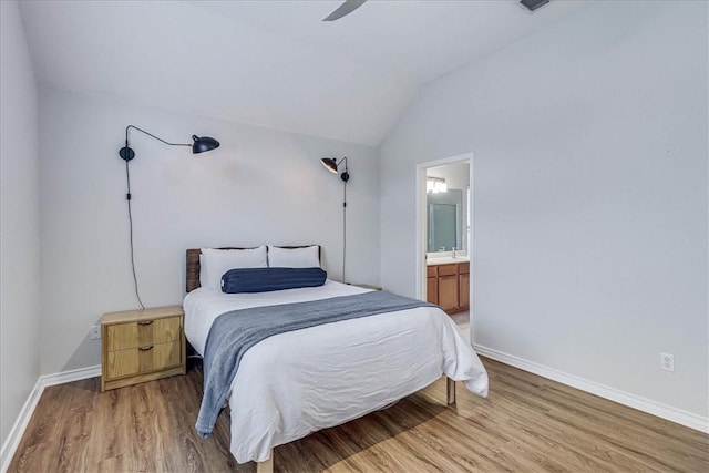 bedroom featuring lofted ceiling, wood finished floors, connected bathroom, and baseboards