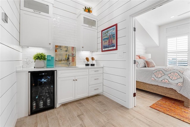 bar featuring wine cooler, white cabinets, and light hardwood / wood-style floors