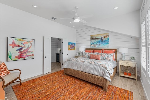 bedroom featuring ceiling fan, wood-type flooring, and wooden walls